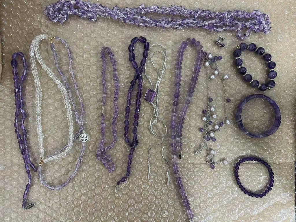多款紫水晶饰品平铺展示,包括项链、手链和小配饰,展示天然水晶的通透质感