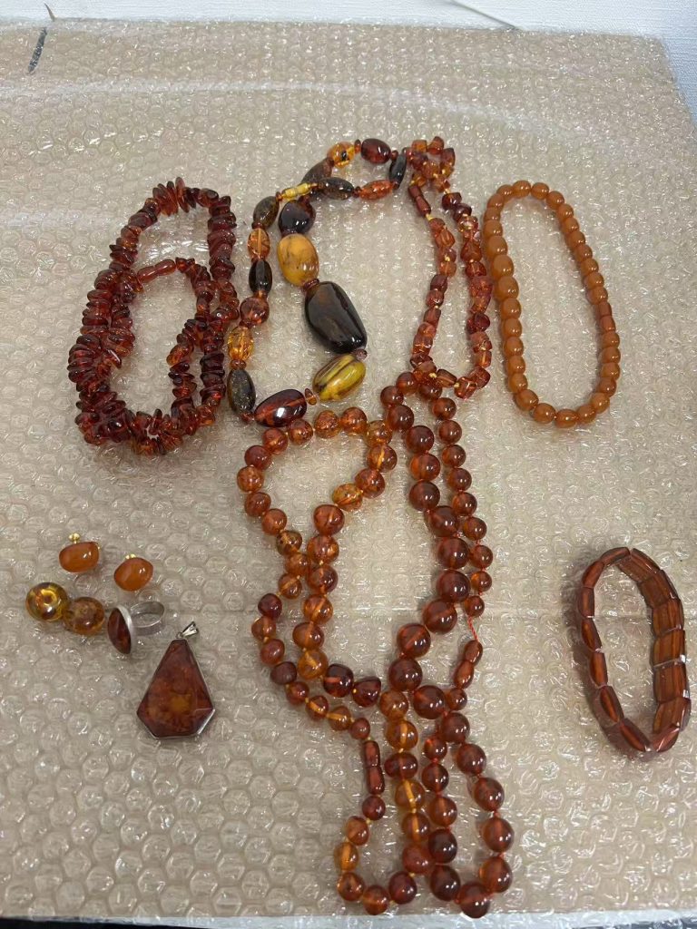 多款琥珀饰品平铺展示,包括项链、耳钉和手串,色泽从浅黄到深蜜色。