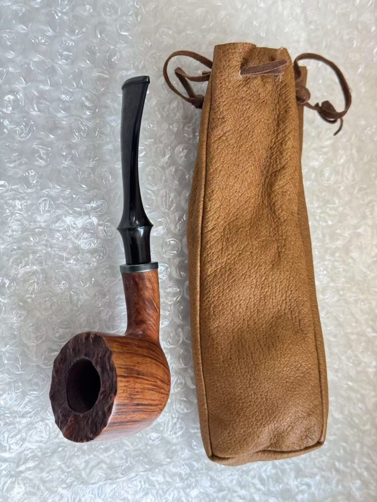 日本代拍手工原木风格烟斗,斗口呈粗糙自然纹理,并附皮质烟斗袋